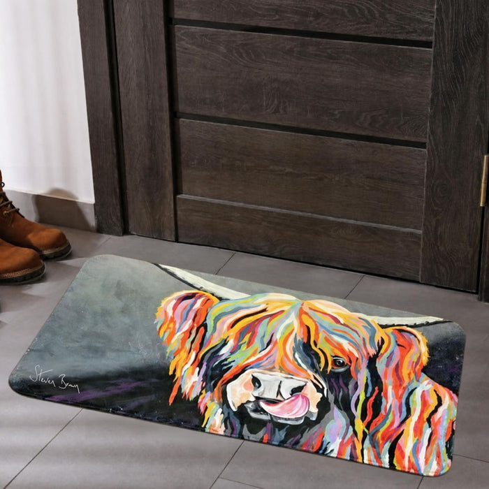 A rectangular floor mat with a colorful painted Highland cow design, placed in front of a dark wooden door on a gray tiled floor. Brown boots are visible on the left edge.